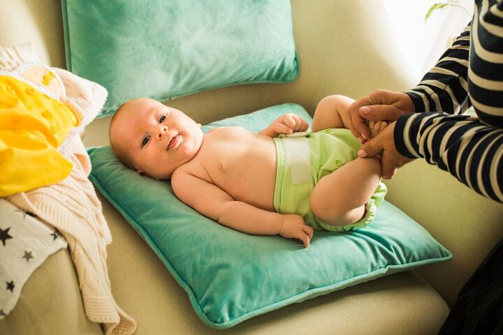 10 common baby items you don t need minimalist parenting, Changing a baby using reusable diapers