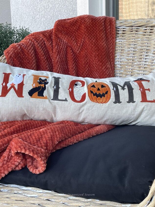 budget decorating ideas for an amazing fall porch, A throw burgundy blanket and Halloween pillow Put them on an outdoor chair for a Budget decorating ideas for fall porch