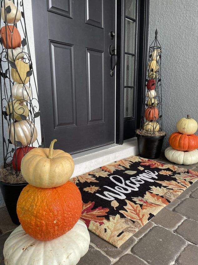 budget decorating ideas for an amazing fall porch, Two pumpkin obelisks on either side of a door A stack of three pumpkins sits in front of each one