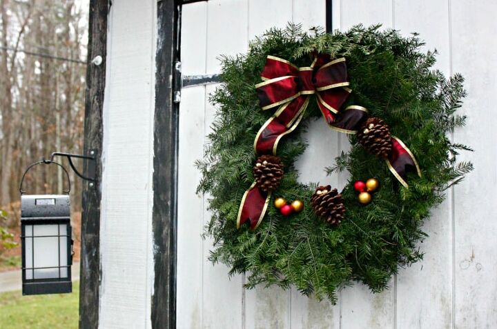 how to have a greener christmas that s more sustainable, a Christmas wreath hanging on a white door