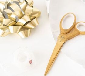 11 easy things to declutter from your gifting supplies, Gold scissors gold gift bow and clear sellotape on white background