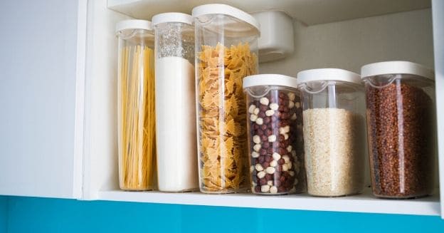 18 frugal home must haves to save money, shelf of filled clear containers with white lids filled with various dried goods to signify my frugal home