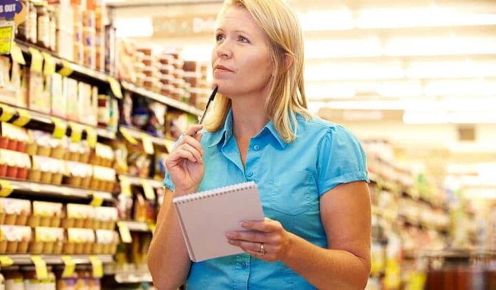 budget grocery list the best cheapest foods for tight budgets, woman thinking about her weekly budget grocery list while in the supermarket