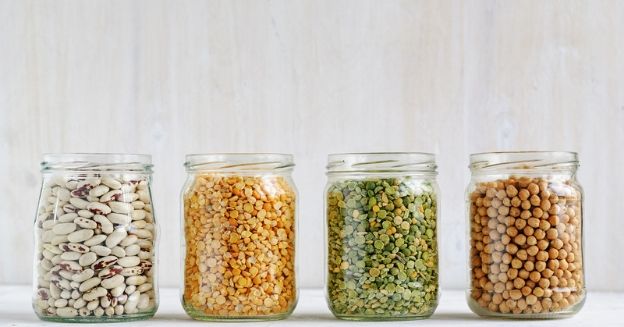 55 best cheap foods to buy when you re broke, 4 glass open lidded glass jars with different pulses filled to the brim to signify best cheap foods to buy when broke