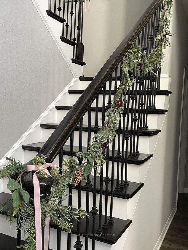 seven ways to decorate for christmas on a budget, An evergreen and eucalyptus garland hanging on a staircase is a good way to decorate for Christmas on a budget
