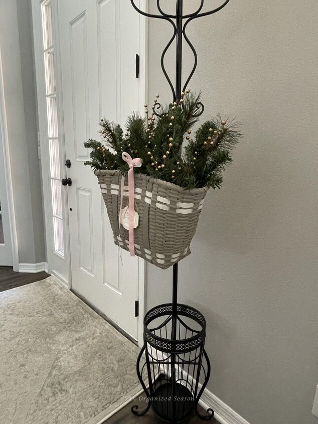 seven ways to decorate for christmas on a budget, A gray basket holding evergreen branches with a pink velvet ribbon is a good way to decorate for Christmas on a budget