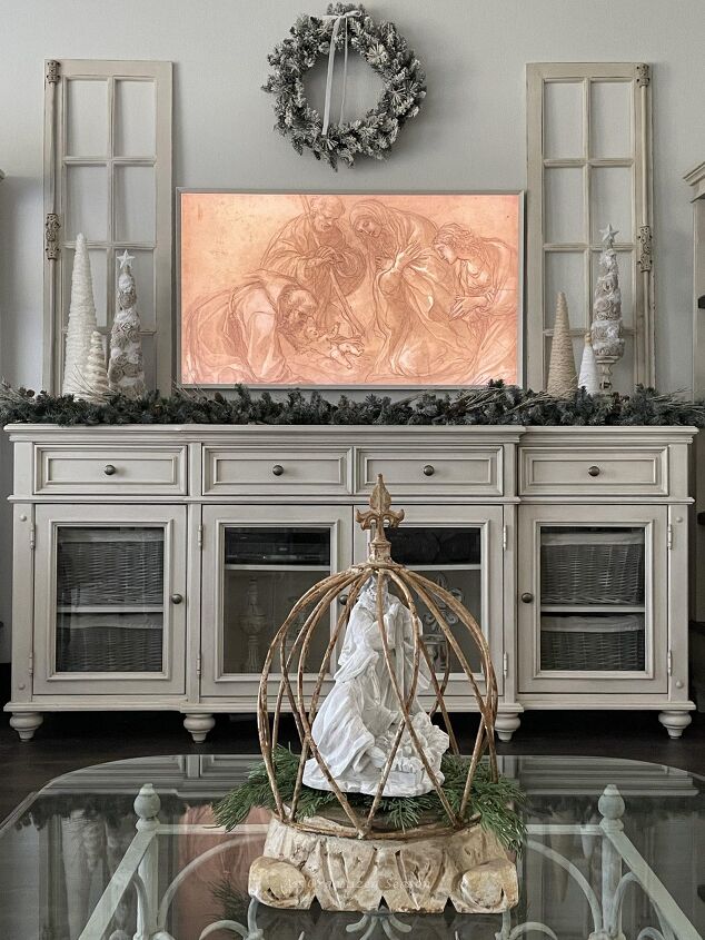 seven ways to decorate for christmas on a budget, A cream console table with a picture frame tv hanging above it displaying the Holy Family