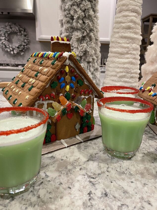 how to get organized for holiday entertaining, A ginger bread house with cups of Grinch punch around it