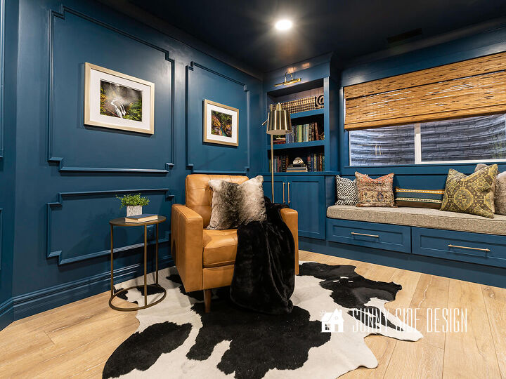 10 sensational home improvement ideas on a budget, Home improvement ideas elegant paneled walls in a deep blue with built in bookshelves window seat leather reading chair cozy cow hide rug