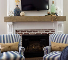 10 sensational home improvement ideas on a budget, White fireplace surround with a faux wood beam mantle brick fireplace box two blue and white striped chairs