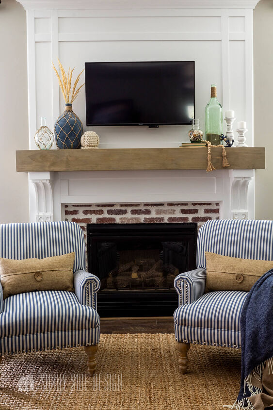 10 sensational home improvement ideas on a budget, White fireplace surround with a faux wood beam mantle brick fireplace box two blue and white striped chairs