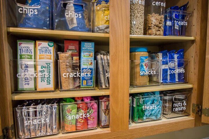 30 affordable pantry organization storage ideas you need to see, Pantry Organization Ideas Clear rectangle containers labeled with white vinyl lettering store packaged food in a cupboard Organized by categories like crackers chips snacks cookies etc