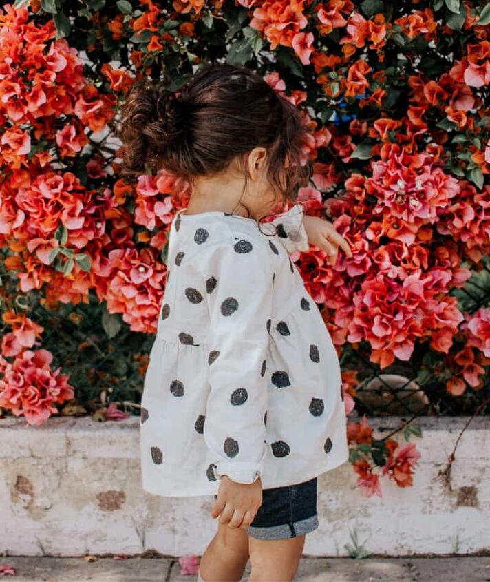 how to save money on kids clothes, girl wearing a cute outfit near pink flowers