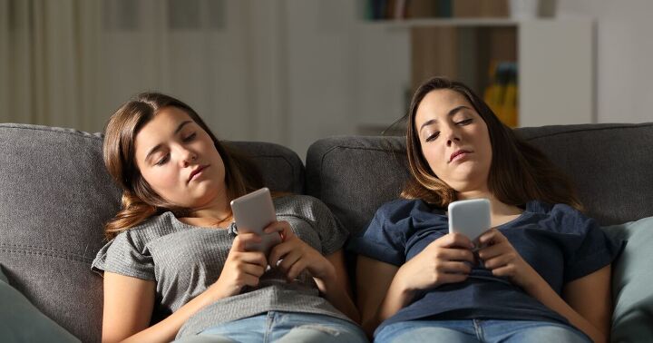 places to go when bored on a budget, Two friends bored on a couch looking at their phones