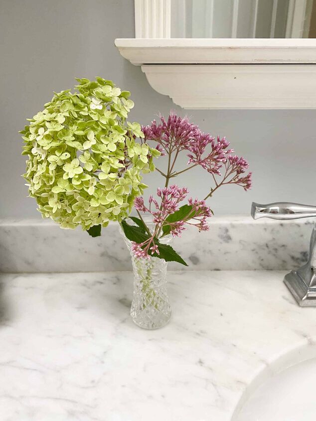 living large in a small house bathroom storage ideas, small Waterford vase with flowers in bathroom on marble countertop