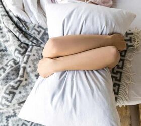 what to do with old pillows, woman hugging new pillow in bed