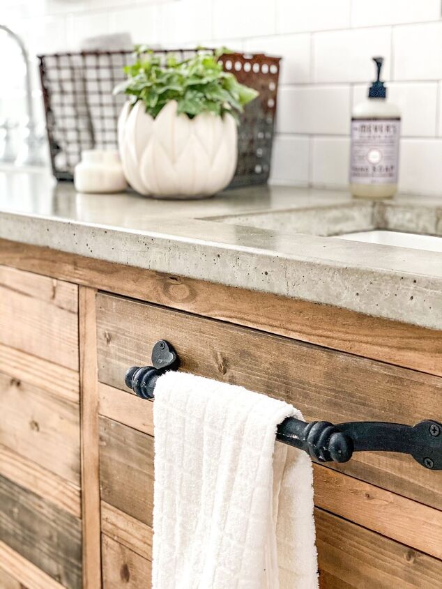 simple decor series how to decorate a small bathroom on a budget, Black towel bar screwed into one of the vanity cabinet doors Simple white towel hangs down in front of image to match the rest of the wood black white concrete them