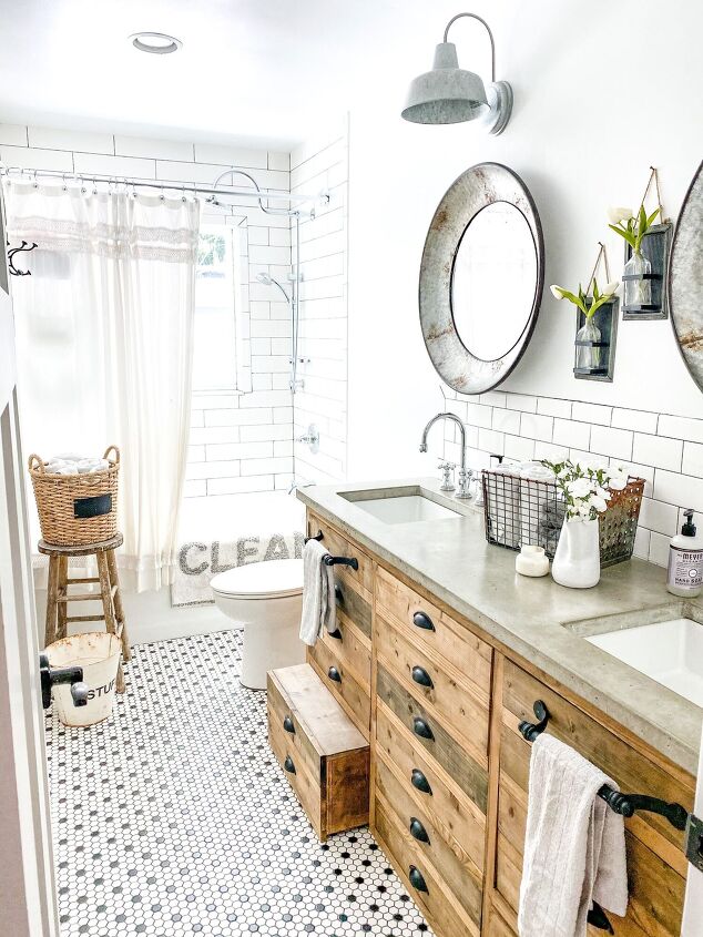 simple decor series how to decorate a small bathroom on a budget, Viewing the right side of the bathroom we see the concrete countertops with round mirrors above The pull out stool in the cabinets is pulled out slightly
