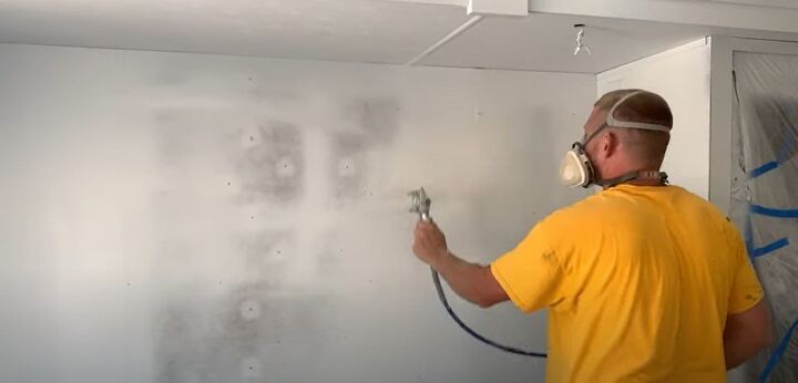 unleash your rv s beauty learn how to paint rv walls like a pro, A man spray painting the walls of an RV with a paint sprayer