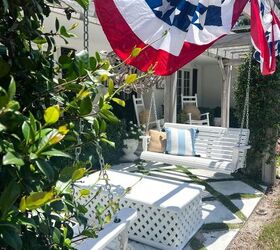 31 easy ideas to decorate a patio or porch for summer, bunting hanging from pergola with summer pillows on the white porch swings