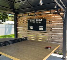 31 easy ideas to decorate a patio or porch for summer, ping pong table under a gazebo and a wooden pallet wall on one side with a black vintage scoreboard