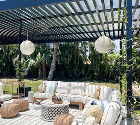 31 easy ideas to decorate a patio or porch for summer, beautiful black pergola with rattan lights hanging from it a large sectional with summer pillows and a beautiful outdoor coffee table